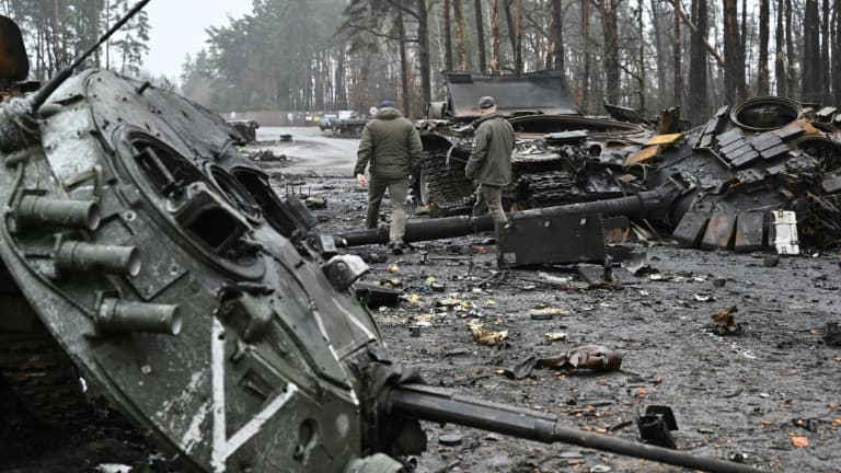 Des militaires ukrainiens marchent entre des chars russes détruits lors de combats à Dmytrivka (ouest de Kiev), le 2 avril 2022 