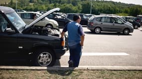 Une personne attend sur l'autoroute à côté de son véhicule en panne. (Illustration)