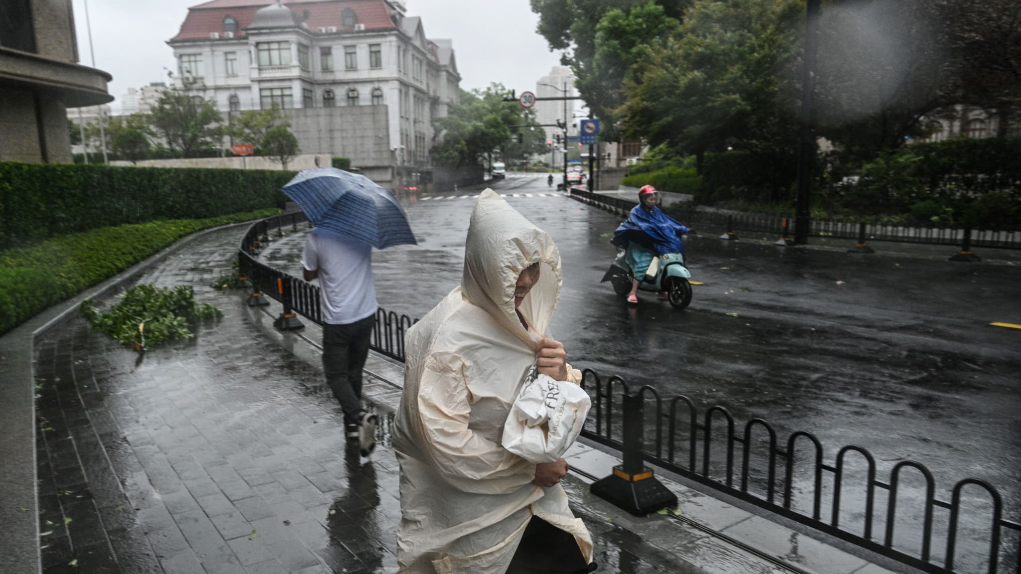 Des piétons et un motocycliste pendant les intempéries causées par le passage du typhon Bebinca à Shanghai, le 16 septembre 2024. 