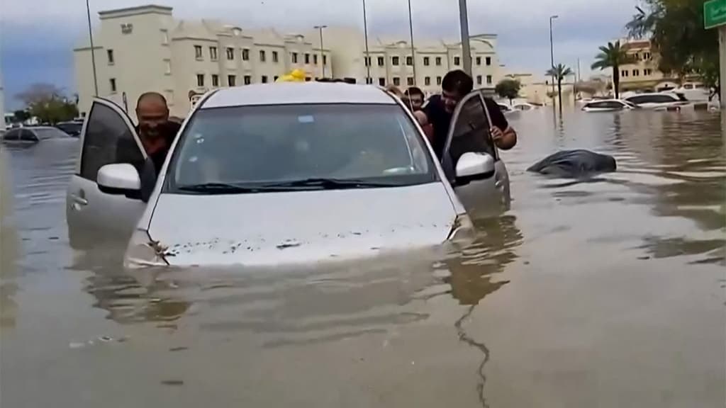 Des gens poussent une voiture bloquée dans une rue inondée à Dubaï le mardi 16 avril 2024. 