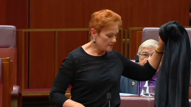Pauline Hanson enlève la burqa qu'elle avait enfilé pour siéger au Parlement australien, le 17 août 2017.