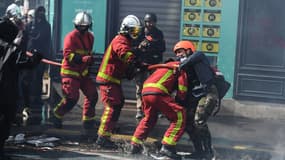 Un sapeur-pompier tentant d'éteindre un incendie agressé par une manifestante alors que des incidents ont éclaté en marge du défilé du 1er mai 2022 à Paris