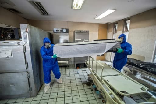 Des employés de Los Olivos Funerales en combinaison intégrale de protection transportent du corps d'une personne décédée du coronavirus, le 1er juin 2020 à Mexico Des employés de Los Olivos Funerales en combinaison intégrale de protection transportent du corps d'une personne décédée du coronavirus, le 1er juin 2020 à Mexico