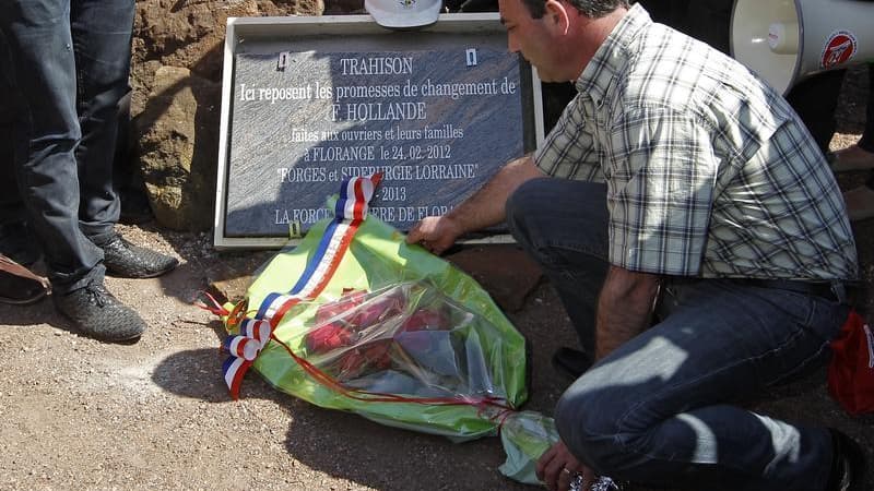 Un ouvrier du site ArcelorMittal à Florange dépose une gerbe de fleurs sur une stèle funéraire placée à l'une des entrées du site sidérurgique, pour enterrer symboliquement les promesses non tenues de François Hollande concernant l'avenir de leur usine. L