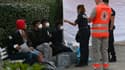 Des policiers et un membre de la Croix-Rouge parlent avec des jeunes migrants secourus par le navire Ocean Viking de l'ONG SOS Méditerranée reçoivent des vêtements de la Croix-Rouge après leur arrivée dans un centre de vacances sur la presqu'île de Giens, le 11 novembre 2022 à Hyères