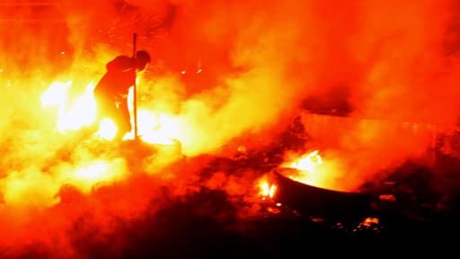 Un manifestant traverse l'un des murs de flammes qui ont été dressés entre leur quartier général et les forces de police.