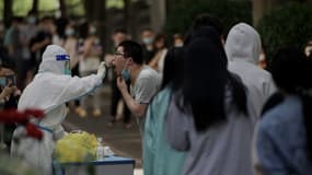 Un agent de santé prélève un échantillon par écouvillonnage sur un homme afin de le tester pour le coronavirus Covid-19 dans un site de collecte d'échantillons à Pékin, le 27 mai 2022 (photo d'illustration).