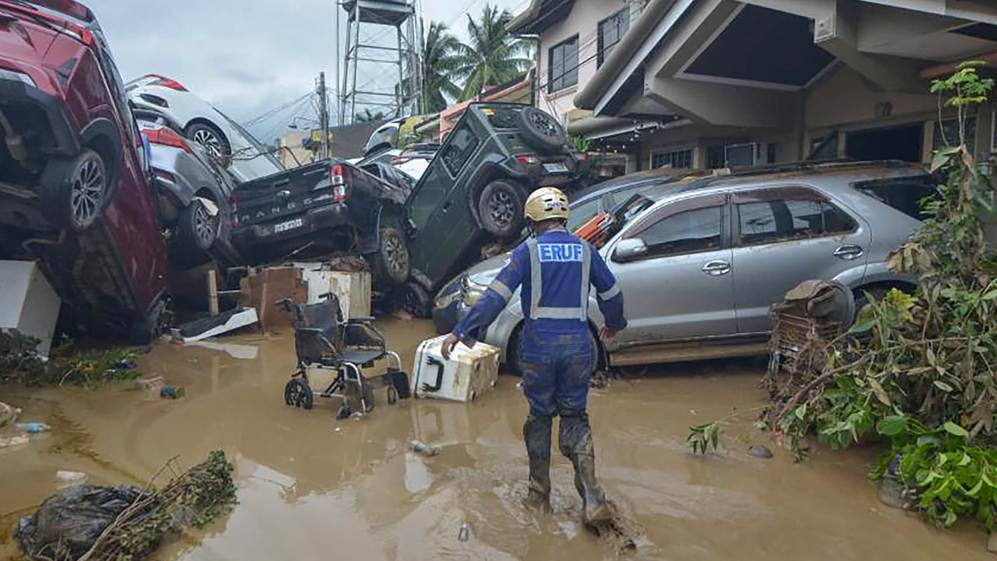 A rescuer walks past stacked cars swept away by floodwaters during the height of Typhoon Kalmaegi in Cebu, Philippines, Nov. 4, 2025.