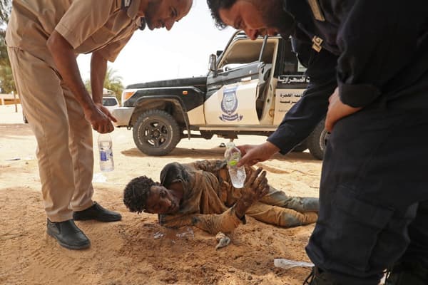 Des gardes-frontières libyens fournissent de l'eau à des migrants, près d'Al-Assah, à la frontière entre la Libye et la Tunisie, le 30 juillet 2023.