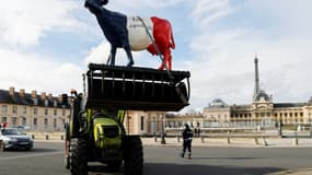 Un producteur laitier transporte avec son tracteur une sculpture géante de vache aux couleurs nationales lors d'une manifestation sur l'esplanade des Invalides, le 13 février 2024 à Paris