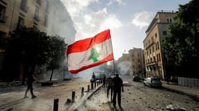 Un protestataire à Beyrouth brandit le drapeau national libanais devant les forces de sécurité pendant une manifestation le 8 août après l'explosion dévastatrice du 5 août