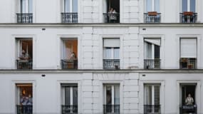 Des personnes à la fenêtre de leurs appartements applaudissent les personnels soignants, le 30 mars 2020 à Paris pendant confinement instauré en France