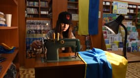Une volontaire ukrainienne cousant un drapeau ukrainien dans une librairie. 
