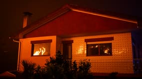 Des flammes se reflètent dans les fenêtres d'une maison lors d'un incendie de forêt à Ribeira de Fraguas, Albergaria-a-Velha à Aveiro, le 16 septembre 2024. 