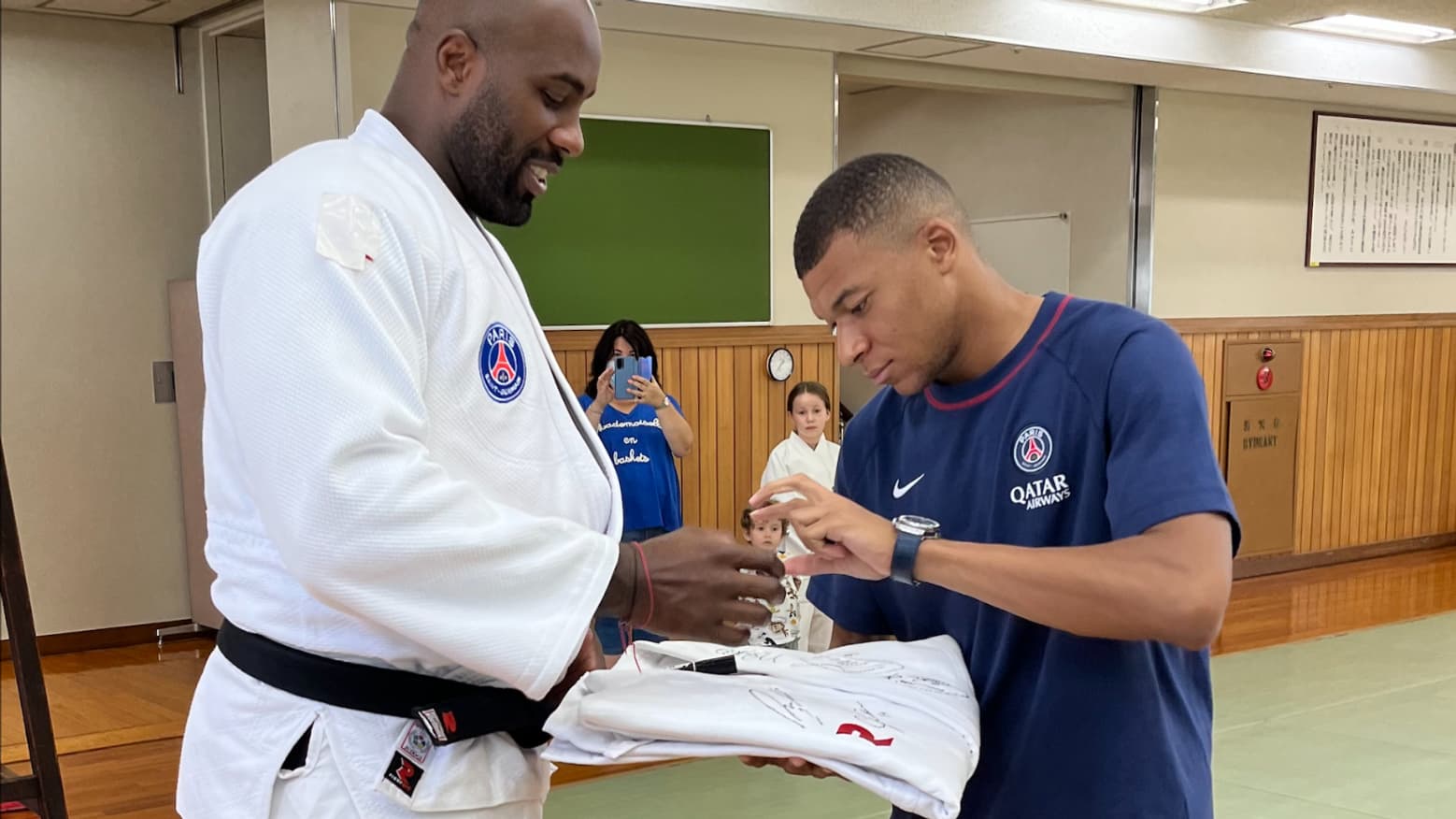Kylian Mbappé signe un autographe sur un kimono tendu par Teddy Riner, ce jeudi 22 juillet 2022 à Tokyo