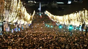 Les parisiens et les touristes rassemblés sur les Champs-Elysées en attendant le feu d'artifice du Nouvel An à Paris le 31 décembre 2022