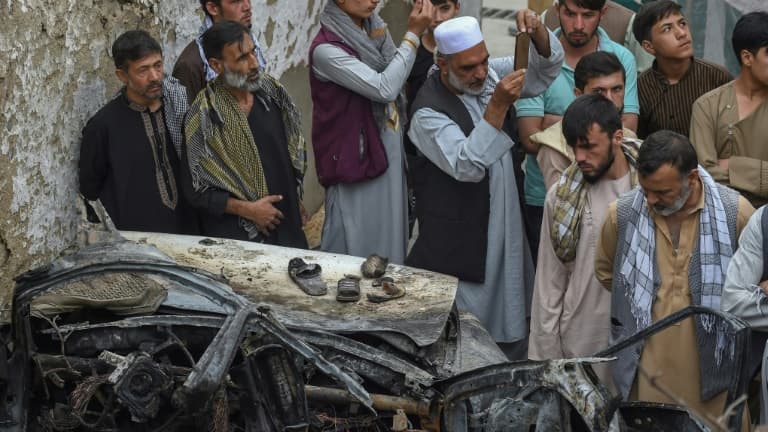 Des proches des victimes d'une frappe américaine sur une voiture - une bavure "tragique" - autour de la carcasse du véhicule, le 30 août 2021 à Kaboul.