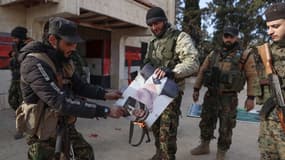 Des combattants ont mis le feu à un portrait du président syrien Bachar al-Assad devant un bâtiment qui a été pris par des jihadistes dans la région de Zarbah le 29 novembre 2024, alors que les jihadistes de Hayat Tahrir al-Sham (HTS) et les groupes alliés poursuivent leur offensive dans la province d'Alep, dans le nord de la Syrie, contre les forces gouvernementales.