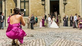 Une photographe de mariage en train d'immortaliser la sortie de la mairie des mariés.