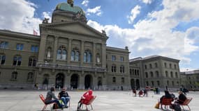 Des gens assis devant l'Assemblée fédérale à Berne, en Suisse, le 14 avril 2021