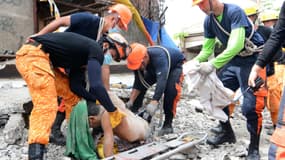 Des secouristes dégagent le corps d'une victime qui a péri sur l'île de Cebu mardi, après le séisme qui a frappé les Philippines.