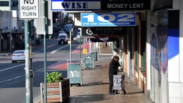 Une femme devant un magasin fermé à Fairfield, dans la banlieue de Sydney, le 12 juillet 2021