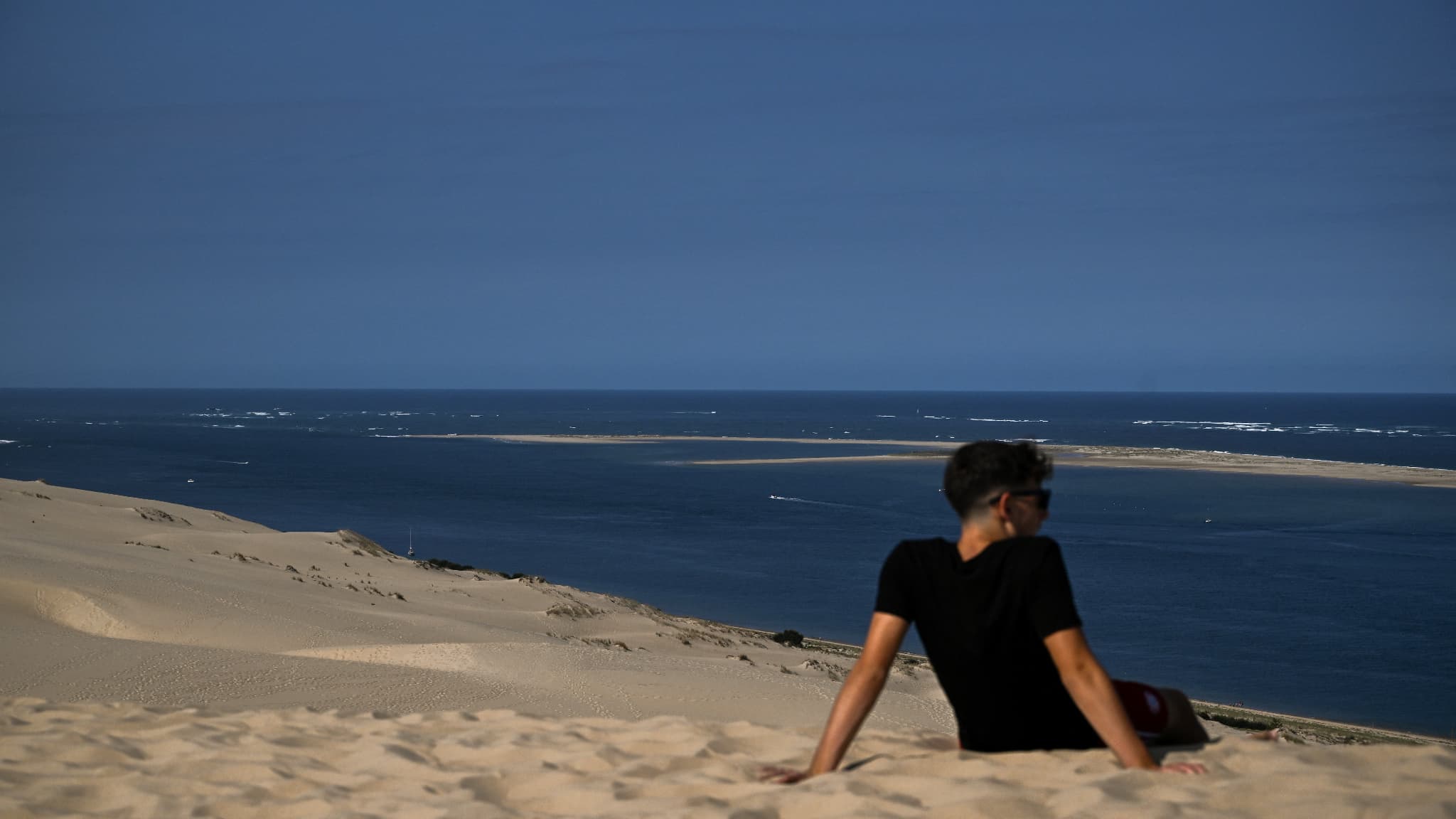 Un homme assis sur la dune du Pilat, la plus haute d'Europe, le 9 juillet 2023.