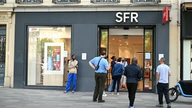 Des personnes se tiennent devant l'agence de l'opérateur de télécommunications français SFR à Paris, le 16 juin 2025.