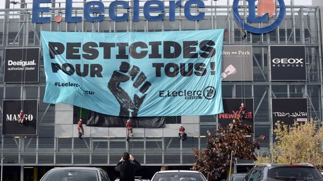 Des militants Greenpeace en train d'installer une banderole sur la façade d'un hyper marché Leclerc situé près de Toulouse.