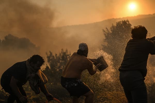 Des habitants tentent d'éteindre un feu de forêt qui s'approche du village de Zambujeiro à Cascais, au Portugal, le 25 juillet 2023.