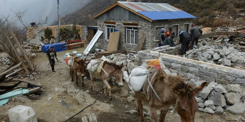 Des Népalais travaillant à reconstruire leur maison, le 7 avril 2016, soit un an après le séisme meurtrier qui a frappé le pays.