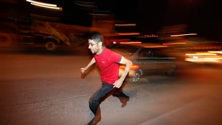 Un manifestant courant se mettre à l'abri alors que l'armée bahreïnie ouvrait le feu près de la place de la Perle à Manama. Des témoins ont rapporté qu'une vingtaine de fourgons de police s'étaient dirigés vers la place de la Perle, où les tirs se poursui