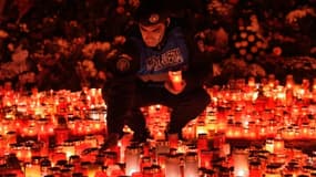 Un gendarme roumain place des bougies en mémoire des victimes de l'incendie d'une discothèque à Bucarest le 2 novembre 2015