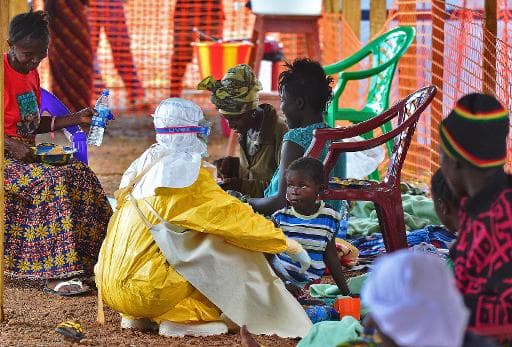 Un employé de Médecins sans frontières (MSF) nourrit un enfant victime du virus Ebola, le 15 août 2014 à Kailahun, au Sierra Leone