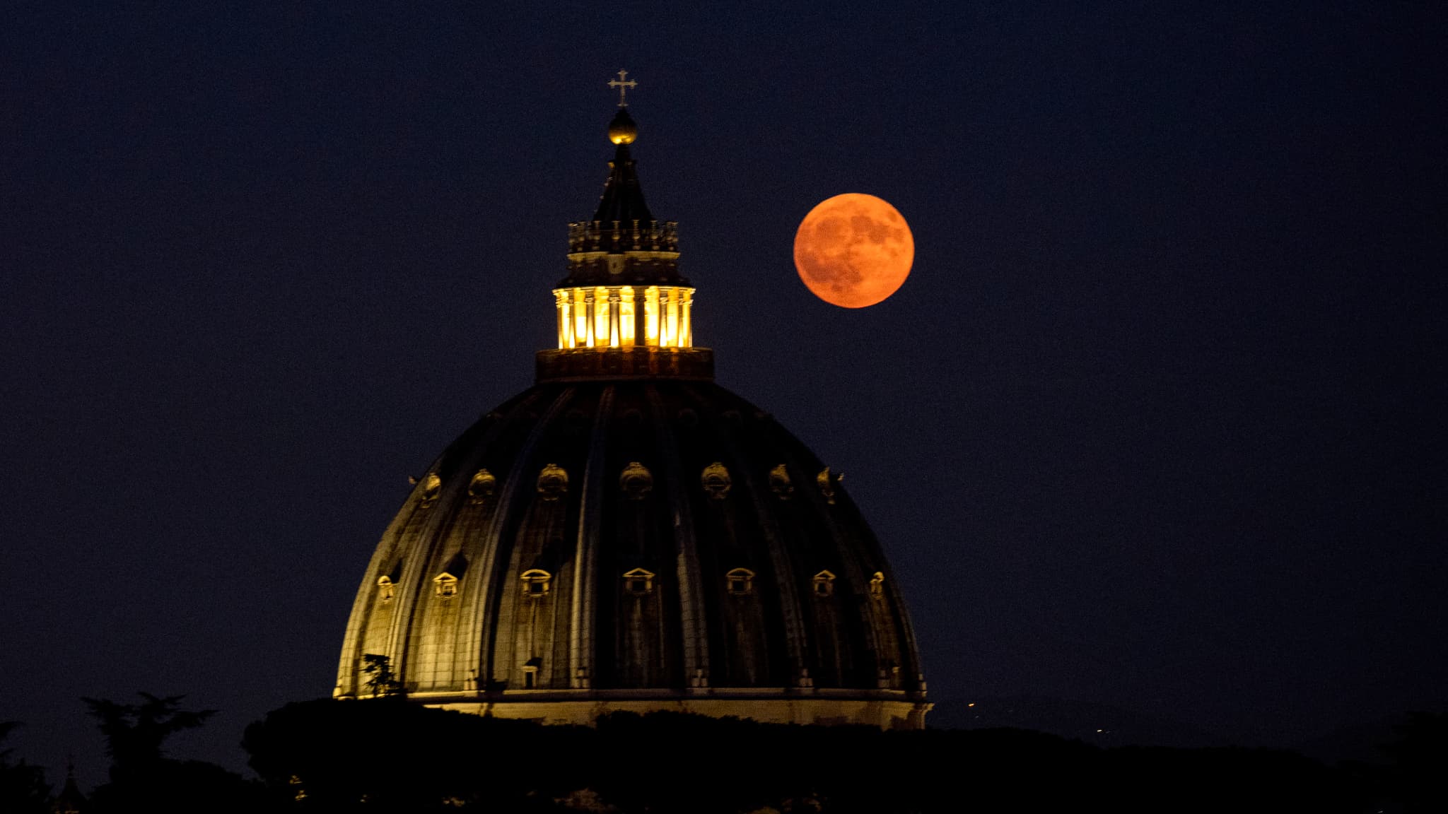 Cette photo prise à Rome montre la Super Lune Bleue se levant au-dessus du dôme de la Basilique Saint-Pierre dans la Cité du Vatican, le 19 août 2024.