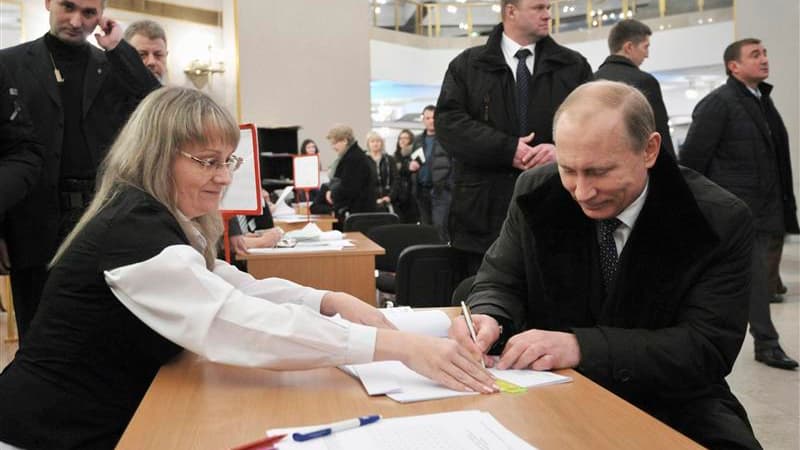 Vladimir Poutine signe la liste d'émargement dans un bureau de vote de Moscou. Le parti Russie unie du Premier ministre et candidat à la présidentielle sortirait large vainqueur des élections législatives de dimanche, selon la télévision d'Etat, tout en e