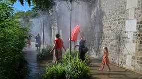 Des personnes se rafraîchissent sous un brumisateur sur les quais de la Seine, pendant un épisode de canicule, le 21 août 2023 à Paris