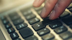 Une personne appuyant sur les touches d'un clavier de PC portable.