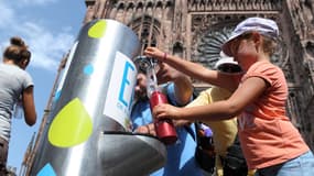 Des personnes remplissent des bouteilles d'eau à une fontaine publique le 20 août 2012, devant la cathédrale de Strasbourg. (Illustration)