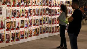Des personnes regardent des portraits d'otages israéliens, détenus à Gaza depuis l'attaque du 7 octobre, affichés sur un mur à Tel Aviv le 23 avril 2024. 
