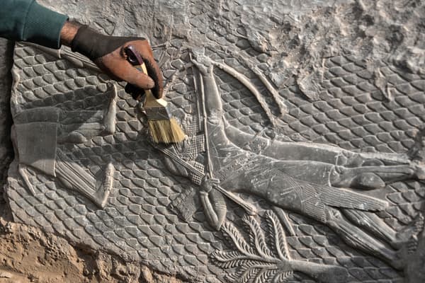 Un travailleur irakien met en lumière un bas-relief découvert à Mossoul, vieux de 2700 ans et représentant des scènes de guerre de l'époque des puissants rois d'Assyrie