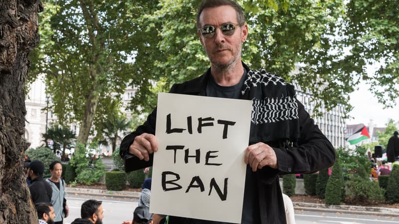 Robert Del Naja, également connu sous le nom de 3D, du groupe Massive Attack, brandit une pancarte "Lift the Ban" (Lève l'interdiction) alors que des centaines de personnes se rassemblent pour participer à une manifestation au Parliament Square contre l'interdiction de Palestine Action à Londres, au Royaume-Uni, le 6 septembre 2025.