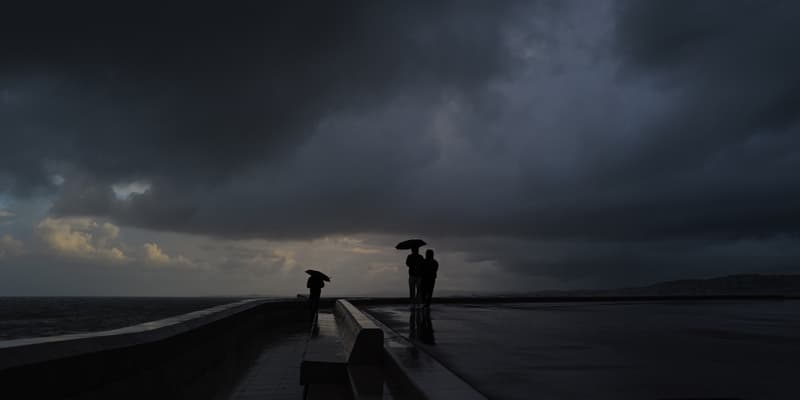 Des personnes se tiennent sous des parapluies pendant une forte pluie à Nice sur la Côte d'Azur, le 3 mars 2024.