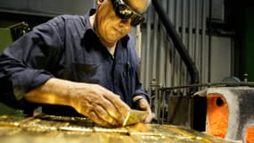 Un employé tient un lingot d'or de 12,5 kg le 6 avril 2009 dans une usine de l'affineur et fabricant de lingots d'or Argor-Heraeus SA à Mendrisio, dans le sud de la Suisse. 