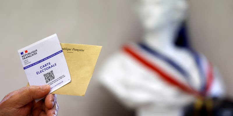 Un électeur tient sa carte électorale et son bulletin de vote face au buste de Marianne, dimanche 19 juin 2022, lors du second tour des élections législatives