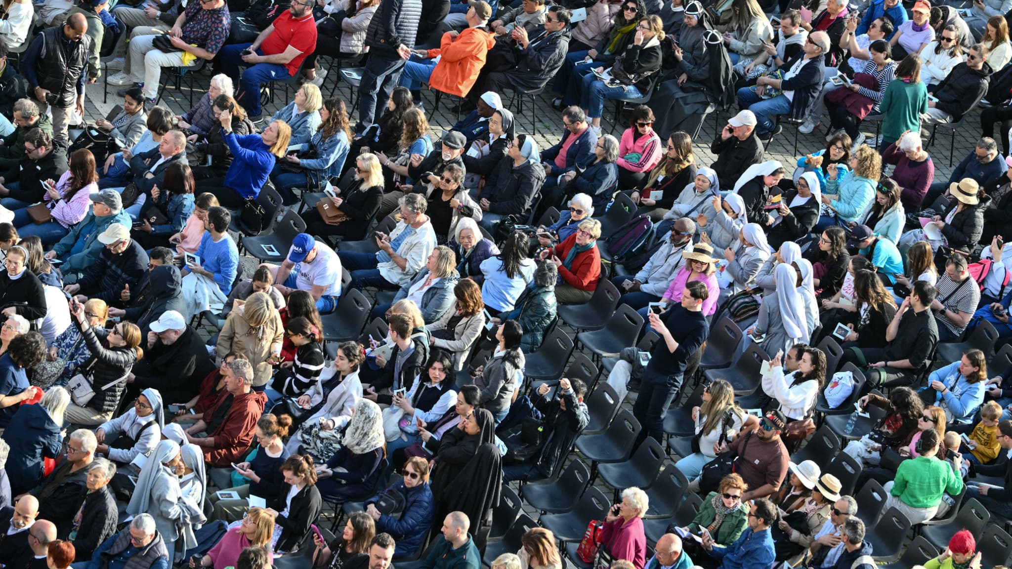 Des personnes présentes sur la place Saint-Pierre avant l'arrivée du cercueil du pape François au Vatican, le 23 avril 2025.