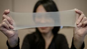 Une femme tire sur l'un des échantillons du plus mince préservatif en latex du monde lors d'une conférence de presse à Hong Kong, le 20 février 2014. Les préservatifs fabriqués par la société chinoise Guangzhou Daming United Rubber Products.