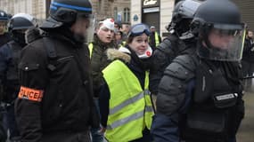 Une manifestante arborant un gilet jaune, interpellée samedi matin, sur les Champs Elysées.