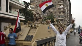 Des Egyptiens saluent mercredi l’action de l’armée dans une rue du Caire.