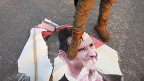 Un combattant anti-gouvernemental marche sur un portrait déchiré du président syrien Bashar al-Assad à Hama, un jour après que les rebelles aient pris la ville du centre-ouest, le 6 décembre 2024.
